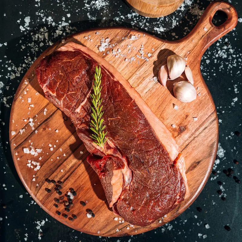 raw sirloin steak on wood cutting board