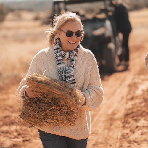 smiling woman in sweater carrying flake of hay