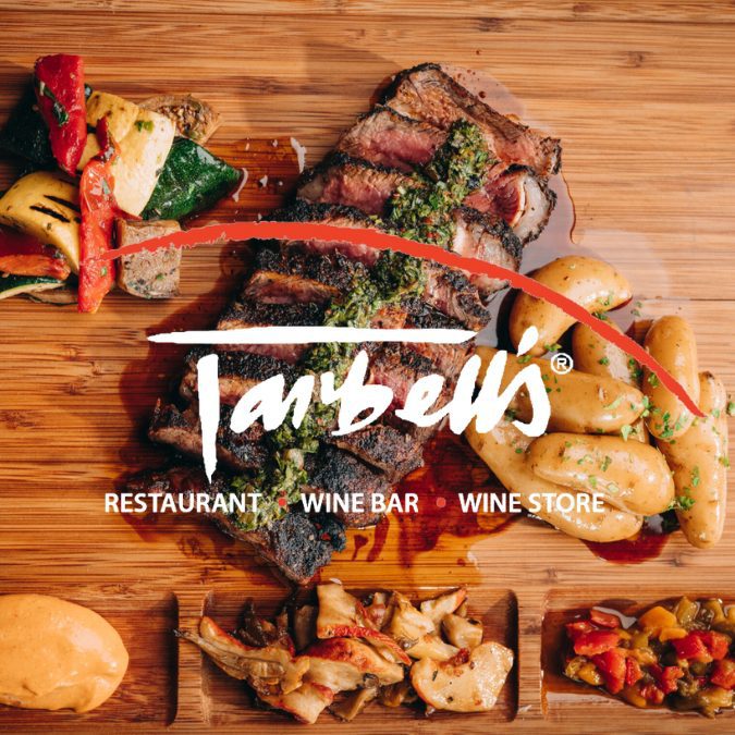 tarbell's logo over a cutting board with cooked steak and side dishes