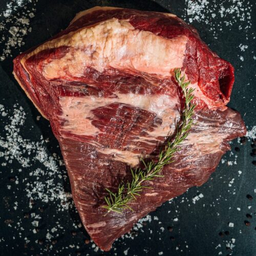 cut of raw brisket with rosemary
